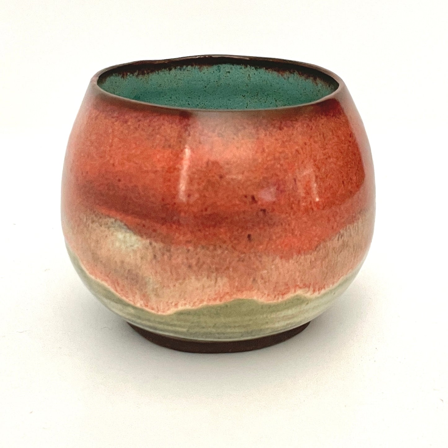 Round red cup with Turquoise interior on Dark Clay