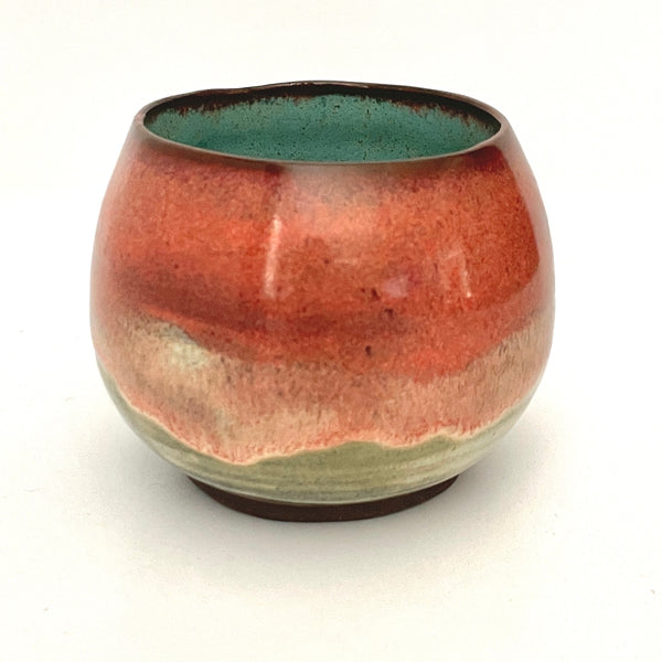 Round red cup with Turquoise interior on Dark Clay