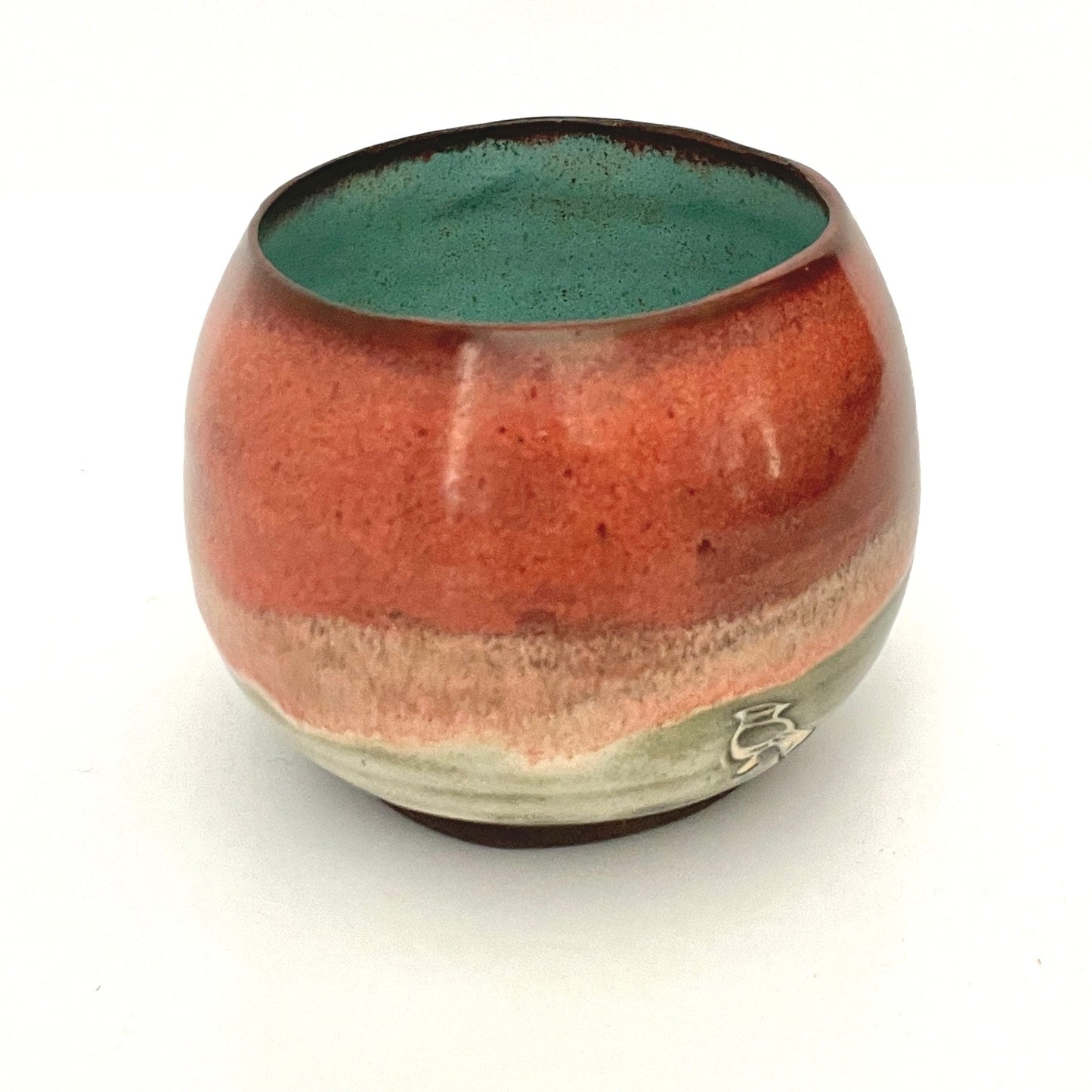 Round red cup with Turquoise interior on Dark Clay