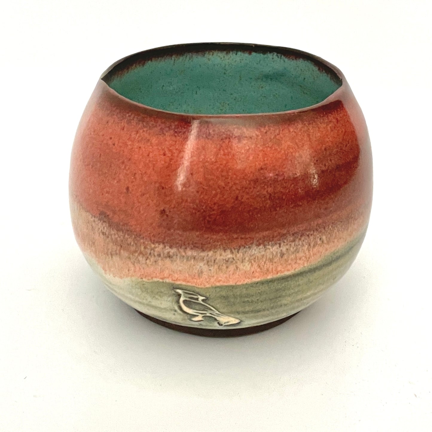 Round red cup with Turquoise interior on Dark Clay