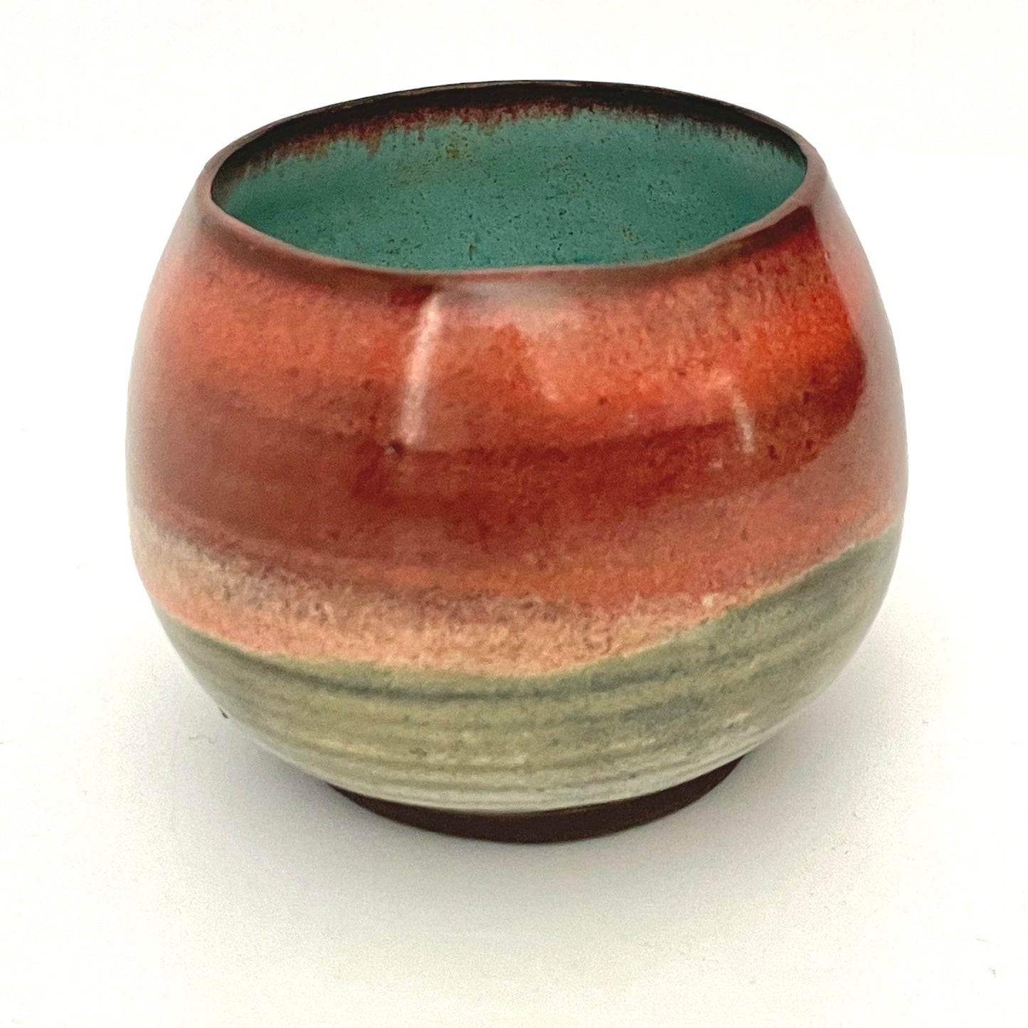 Round red cup with Turquoise interior on Dark Clay