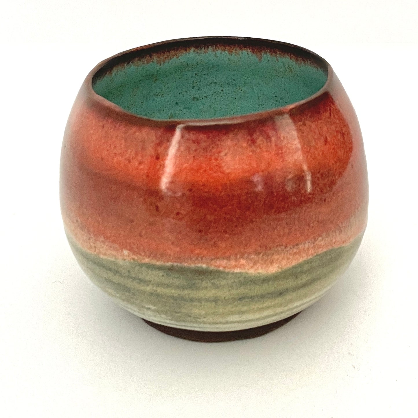 Round red cup with Turquoise interior on Dark Clay