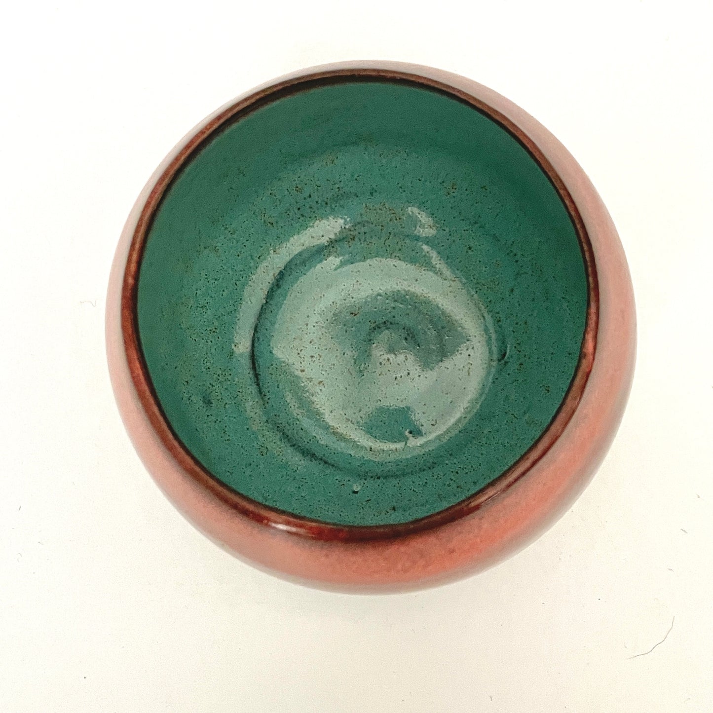 Round red cup with Turquoise interior on Dark Clay