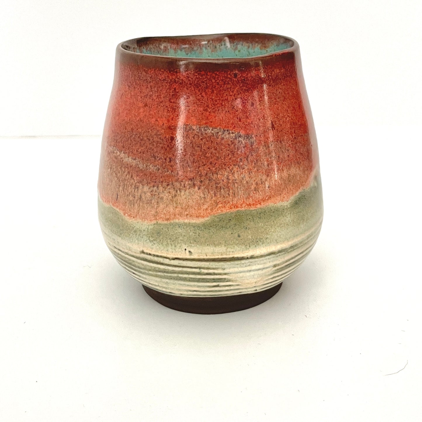 Red and Cream cup with Turquoise interior on Dark Clay