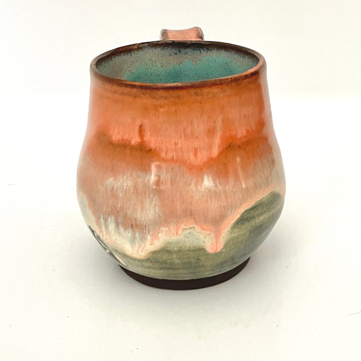 Orange and Cream mug with Turquoise interior on Dark Clay