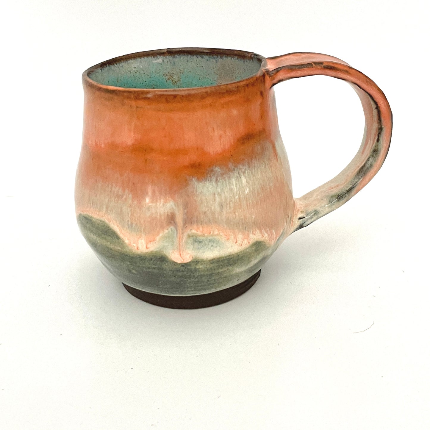 Orange and Cream mug with Turquoise interior on Dark Clay