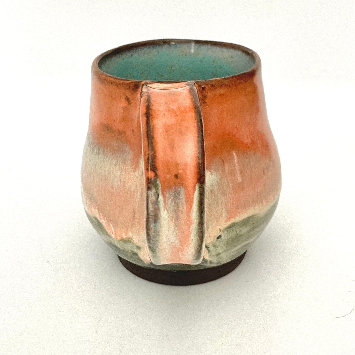 Orange and Cream mug with Turquoise interior on Dark Clay